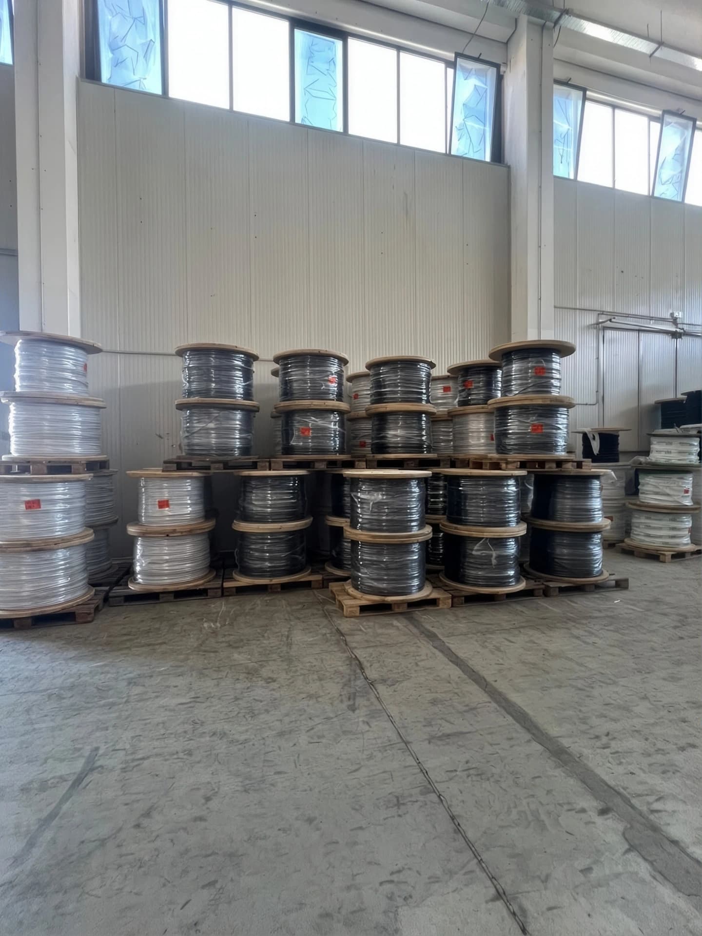 Bobine di cavo bianco e nero su pallet nel capannone